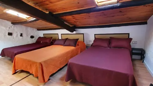 Bonita habitación de estilo rústico con tres camas dobles y un total de 6 plazas para huéspedes en la casa rural Cal Curpets.